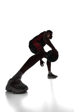 Silhouette of young man, basketball player in motion, training, playing, dribbling ball isolated on white background. Concept of professional sport, competition, game, tournament, action clipart