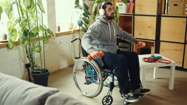 Молодий Чоловік Сидить Інвалідному Кріслі Навушниках Тренується Займається Вправами Гантелями — стокове відео