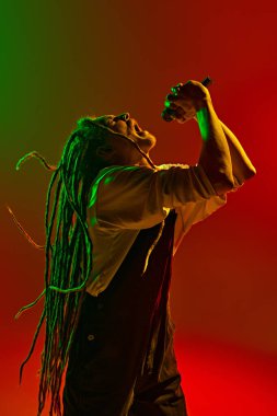 Duygulu bir müzisyen. Rastalı saçlarıyla en derin duygularını şarkı söyleyerek neon ışıkta yeşil arkaplan rengine karşı ifade ediyor. Müzik, performans, festival, konser kavramı