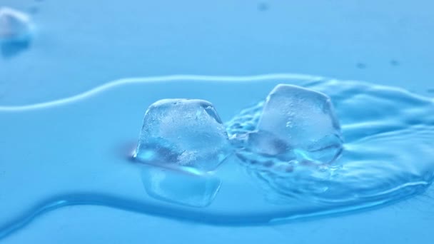 水で満たされた透明なガラスで溶ける2つの氷の立方体 クリスタル クリア ドロップレット リフレッシュとクールさ リフレッシュのコンセプト 製品の美学 水分補給 — ストック動画
