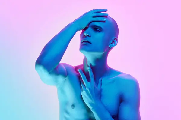 stock image Self-identity. Portrait of young man with bald head, posing shirtless on gradient blue pink background in neon light. Concept of male beauty, body, youth, fitness, sport, health