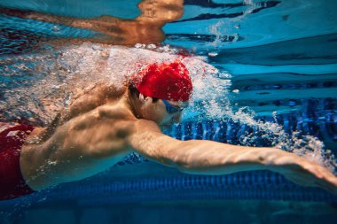 Disiplin ve odaklanma. Kırmızı teneke giyen kaslı, atletik genç adam ve hareket halindeki gözlükler, havuzda yüzme, antrenman. Profesyonel spor, sağlık, dayanıklılık, güç, aktif yaşam tarzı kavramı