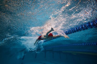 Sınırsız enerji ve motivasyon. Atletik genç bir adam, şapkalı bir yüzücü ve kapalı havuzda hareket gözlüğü takıyor. Profesyonel spor, sağlık, dayanıklılık, güç, aktif yaşam tarzı kavramı
