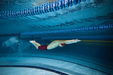Kelebek yüzme stili. Atletik genç adam, hareket eğitiminde yüzücü, yarışmaya hazırlanıyor, kapalı havuzda yüzüyor. Profesyonel spor, sağlık, dayanıklılık, güç, aktif yaşam tarzı kavramı