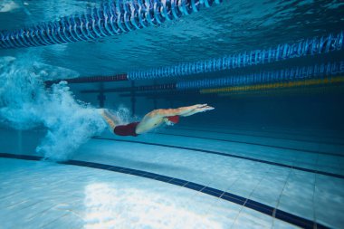 Su kabarcıkları hız gösteriyor. Genç adam, havuz eğitiminde yüzme sporcusu, yarışmaya hazırlanıyor. Profesyonel spor, sağlık, dayanıklılık, güç, aktif yaşam tarzı kavramı