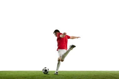 Beyazların arka planında izole bir şekilde topa vurarak futbol maçında hareket eden odaklanmış ve rekabetçi genç bir futbolcu. Profesyonel spor, oyun, yarışma, turnuva, aksiyon konsepti