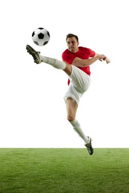 Kırmızı ve beyaz üniformalı uzun boylu genç bir adam, atlamada topa vuran bir futbolcu, beyaz arka planda izole edilmiş bir eğitim. Profesyonel spor, oyun, rekabet, turnuva, aksiyon kavramı