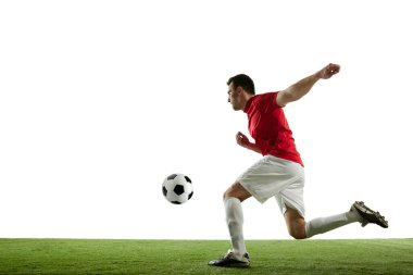 Genç bir adamın dinamik görüntüsü, top oynayan, koşan, beyaz arka planda izole edilmiş antrenman yapan futbolcu. Profesyonel spor, oyun, rekabet, turnuva, eylem, aktif yaşam tarzı kavramı