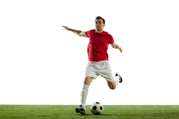 Dynamic image of young man, football player in motion with ball during game isolated on white background. Concept of professional sport, game, competition, tournament, action, active lifestyle