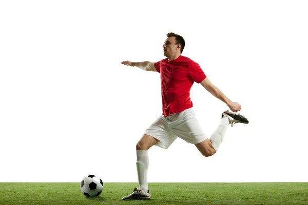 Focused and competitive young male soccer player in motion during football game on field, hitting ball isolated on white background. Professional sport, game, competition, tournament, action concept