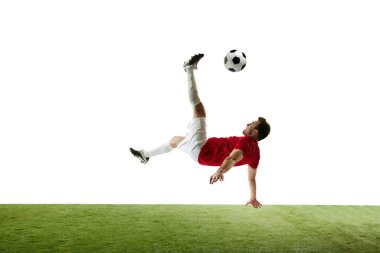 Genç bir adam, maç sırasında hareketli bir futbolcu, antrenman yapıyor, topa vuruyor ve beyaz arka planda tek başına düşüyor. Profesyonel spor, rekabet, turnuva, aksiyon, aktif yaşam tarzı kavramı