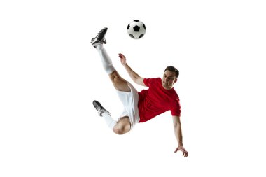 Rekabetçi bir adam, topla hareket eden bir futbolcu, sıçrama yapıyor ve beyaz arka planda izole bir şekilde yere düşüyor. Profesyonel spor, oyun, rekabet, turnuva, aktif yaşam tarzı kavramı