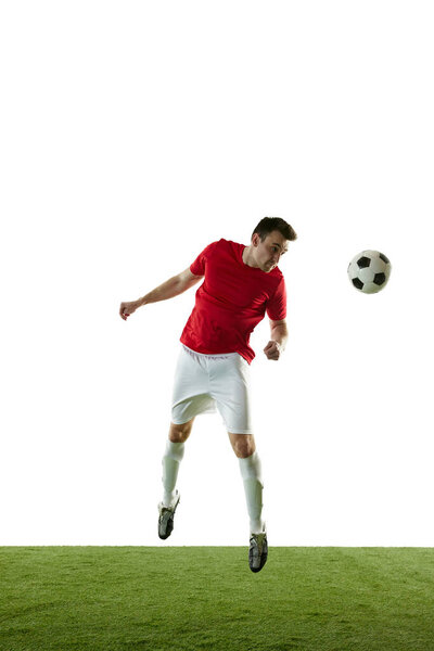 Full-length image of male football player in motion on field, training, hitting ball with head isolated on white background. Concept of professional sport, game, competition, tournament, action