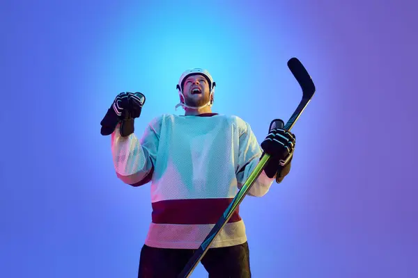 Mann Eishockeyspieler Mit Helm Uniform Und Stock Drücken Vor Blauem Stockbild