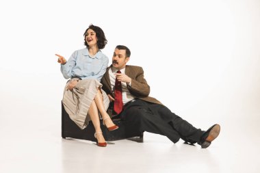 Klasik retro giysiler içinde zarif genç kadın ve erkek oturuyor, başka tarafa bakıyor, işaret ediyor ve alıyor, beyaz arka plan. Tartışmalar, dedikodular, dedikodular. Eski ve eski moda kavramı, moda, duygular