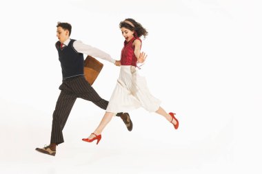 Mutlu genç insanlar, retro elbiseli erkekler ve kadınlar el ele tutuşup beyaz arka planda soyutlanmış bir şekilde koşuyorlar. Retro ve vintage kavramı, moda, insan duyguları, ilişki