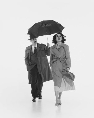 Zarif bir erkek, erkek şemsiyesini ona uzatan ceketli genç bir kadın. İlişki. Monokrom görüntüsü. Retro ve vintage kavramı, moda, insan duyguları, yaşam tarzı