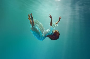 Falling into unknown. Surreal underwater creative scene featuring elegant young woman levitating gracefully underwater. Concept of surrealism, beauty, mystery and fantasy, freedom clipart