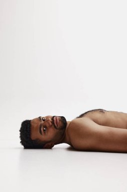 Beyaz arka planda tişörtsüz, yakışıklı, Afro-Amerikan sakallı adam. Erkek güzelliği, spor, vücut bakımı, sağlık, spor
