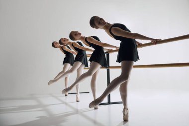 Harmony hareket halinde. Güzel genç kızlar, dans stüdyosuna katılan bale dansçıları, gri arka planda prova yapanlar. Zarafet. Bale, sanat, dans stüdyosu, klasik tarz, gençlik kavramı.