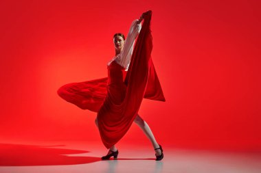 Kadın artistik flamenko dansçısı çarpıcı bir kırmızı arka plana karşı tutku gösteriyor. Zarif duruş ve akıcı etek yoğun dans duygularını gösteriyor. Hareket sanatı, klasik dans, güzellik kavramı