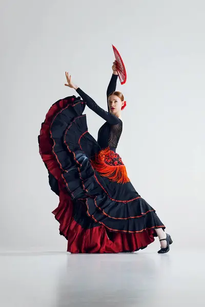 令人惊叹的优雅在运动 女性弗朗明哥舞者身穿黑色衣服 红色的细节生机勃勃 用扇子进行艺术表演 运动艺术的概念 古典舞蹈 — 图库照片