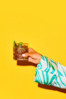 Viskili kadın el bardağı, parlak sarı arka planda naneyle süslenmiş eski moda kokteyl. İçki, parti, tatil, bar, karışım kavramı. Poster. İlan için alanı kopyala