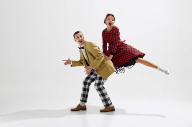 Tarz sahibi genç bir çiftin dinamik görüntüsü. Beyaz stüdyo arka planında izole edilmiş retro temalı dans eden kadın ve erkek. Sanat anlayışı, retro ve vintage, hobi, eğlence, 20 'ler