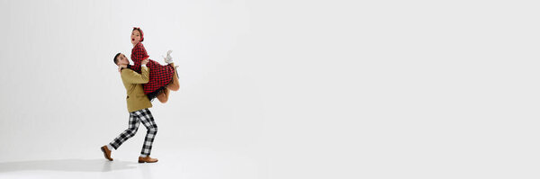 Динамичный образ стильной молодой пары, мужчины и женщины в ретро-тематической одежде, танцующей изолированно на белом фоне студии. Искусство, ретро и винтаж, хобби, развлечения, 20-е годы. Баннер