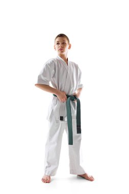 Beyaz stüdyo arka planında izole edilmiş yeşil kuşaklı beyaz kimonolu bir karate atleti. Spor anlayışı, dövüş sanatı, dövüş sporu, sağlıklı ve aktif yaşam tarzı