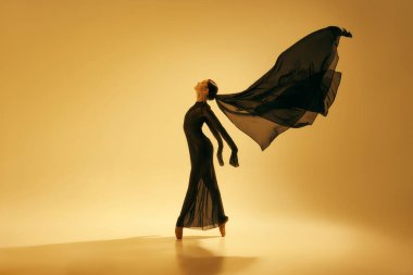 Çağdaş bale gösterisi. Kadın dansçı, sarı arka plana karşı güçlü ve duygusal bir performans sergiliyor. Sanat kavramı, klasik dans, güzellik ve moda, estetik.
