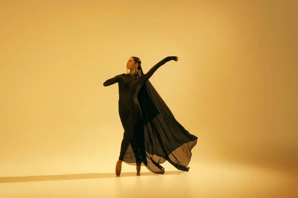 优雅优雅的动作 美丽的芭蕾舞演员穿着典雅的黑色服装 配以金色配饰 衬托着沙色的背景 艺术概念 古典舞蹈 美与时尚 — 图库照片#