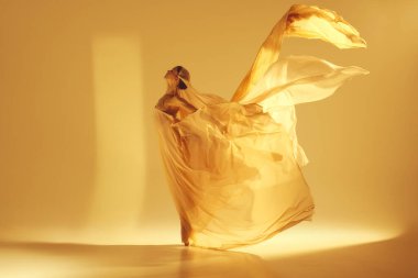 Hareket halindeki balerinin sanatsal tasviri, kum rengi arka planda dans eden zarif bir kadın. Altın rüyanın girdapları. Sanat kavramı, klasik dans, güzellik ve moda, estetik.