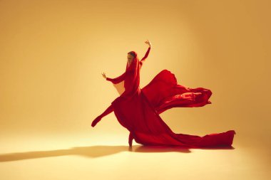 Hareketin sözleri, zarif kadın, yüzü kum rengi arka planda dans eden kırmızı akıcı elbiseli kadın dansçı. Sanat kavramı, klasik dans, güzellik ve moda, estetik.