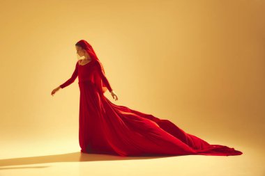 Güç ve zarafet. Akan kırmızı elbise ve yüz aksesuarları giyen zarif bir kadın kum rengi arka planda performans sergiliyor. Sanat kavramı, klasik dans, güzellik ve moda, estetik.