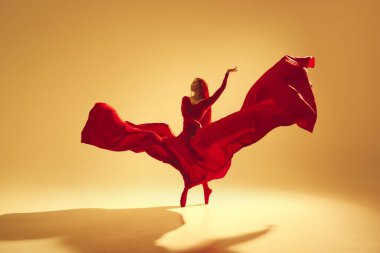 Sanatsal ve derin performanslı kadın, akıcı kırmızı elbiseli kadın dansçı, altın renkli arka planda dans ediyor. Sanat kavramı, klasik dans, güzellik ve moda, estetik.