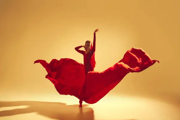 艺术性强 表演深度强的女舞蹈演员 穿着飘逸的红衣服 在金色的背景下跳舞 艺术概念 古典舞蹈 美与时尚 — 图库照片