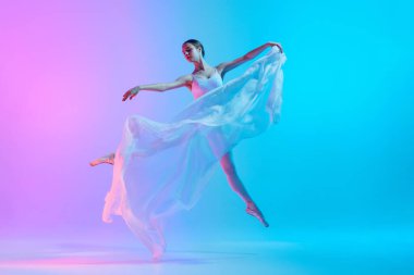 Beyaz kumaşla dans eden sanatçı balerin parlak arka planda neon ışıkta dans ediyor. Zarif bir an. Sanat, hareket, klasik ve modern birleşme, güzellik, moda kavramı.