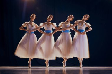 Çekici genç kızlar, beyaz etekli bale dansçıları sahnede dans ederken mavi kurdeleli kızlar. Hareket bulanıklığı efektli fotoğraf. Güzellik kavramı, klasik ve modernlik, çağdaş sanat. Ad