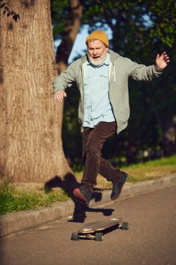 Eski okul patencisi. Son sınıf öğrencisi şık kıyafetler içinde parkta aktif bir sabahın tadını çıkarıyor, boş yolda kaykay yapıyor. Spor anlayışı, yaşlanma, aktif ve sağlıklı yaşam tarzı, sağlık hizmetleri