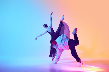Bale ve sokak dansı karışımı. Siyah elbiseli güzel bir kız, genç adamla dans eden bir balerin, neon arka planda hip hop sanatçısı. Klasik ve modern dans kavramı, performans