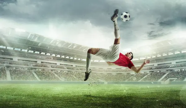 Challenging goal. Man, soccer player in motion during game hitting ball and falling down on grass. Winning match. 3D stadium. Concept of sport, competition, tournament, games, event