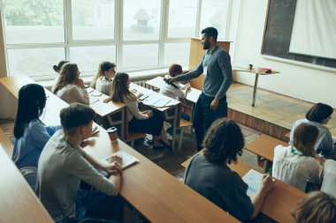 Genç adam, konuşmacı genç kızla konuşuyor. Gençlerle ve üniversitedeki öğrencilerle toplantı yapan bir öğretim üyesi. Eğitim kavramı, gençlik, atölye, bilgi