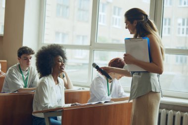 Öğretim görevlisi atölyeye katılan öğrencilerle etkileşim içinde. İyi aydınlatılmış üniversite konferans salonu. Öğrenci değişimi. Eğitim kavramı, gençlik, atölye, bilgi