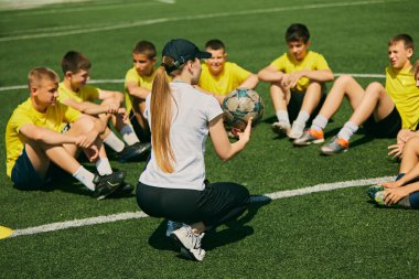Açık hava spor eğitimi. Spor kıyafetli çocuklar açık hava futbol sahasında oturup koçlarının talimatlarını dinliyorlar. Gençlik sporlarında öğretmenlik zamanı. Spor anlayışı, okul, aktif yaşam tarzı