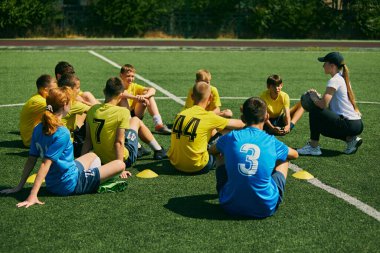 Aktif Gençlik Nişanı. Çocuklar çimenlerde oturuyor ve bayan futbol koçunun talimatlarını dinliyor, futbol stratejileri ve yetenekleri öğreniyorlar. Spor, okul, çocukluk, aktif yaşam tarzı konsepti