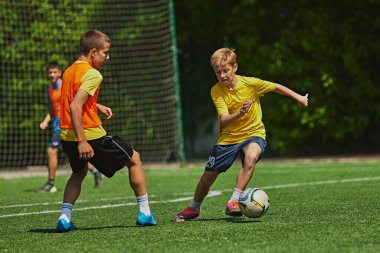 Outdoor Soccer Game. Teen boys in motion during soccer game, playing, raining on green field. Growing skills and endurance. Concept of sport, school, childhood, hobby, active lifestyle clipart