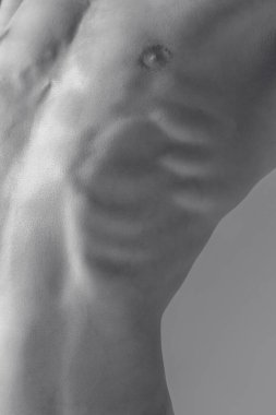 Erkek kaslı vücudunun tek renkli görüntüsü. Soyut Anatomi. Gölgelerden ve ışıktan oluşan bir manzarada insan doğal kas gövdesi. Vücut estetiği, insan doğası ve güzelliği kavramı.