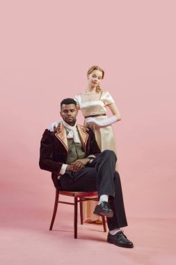 Zengin kadife ceketli kraliyet centilmeninin klasik asil portresi. Pembe stüdyo arka planında güvenle duran bir bayan. Tarih kavramı, retro ve vintage, çağların karşılaştırması