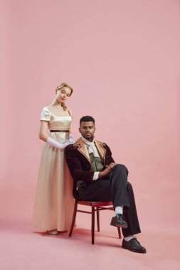 Rönesans Sanatı. Dönem kostümlü güzel bir kadın ve yakışıklı bir adam pembe stüdyo geçmişine karşı poz veriyorlar. Tarih kavramı, retro ve vintage, çağların karşılaştırması